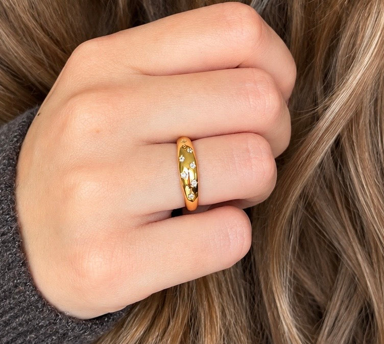 Woman wearing a gold star engraved dome ring in 18k gold-plated S925 sterling silver on her hand. Lifestyle shot with cubic zirconia star details.
