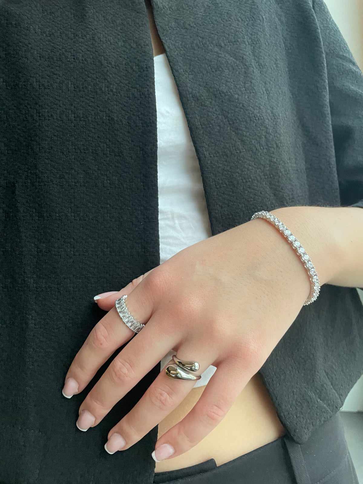 Woman wearing silver open drop ring and tennis bracelet on wrist