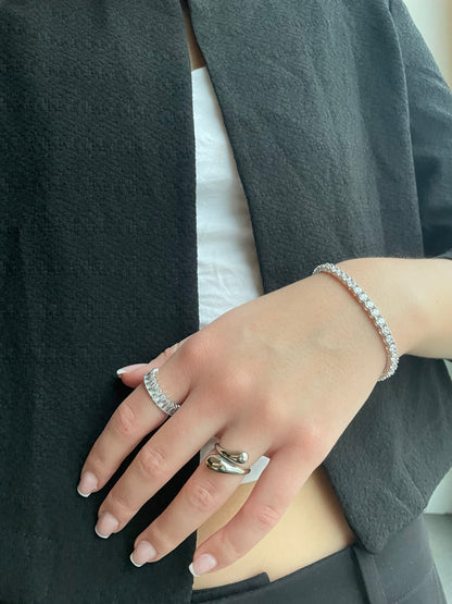 Woman wearing silver open drop ring and tennis bracelet on wrist
