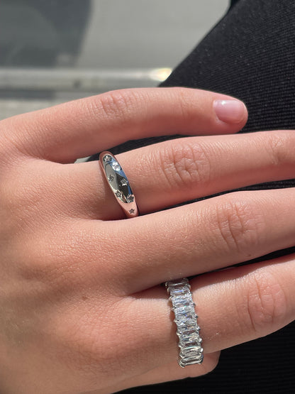 Woman wearing silver star engraved dome ring and baguette cubic zirconia eternity ring stacked on hand
