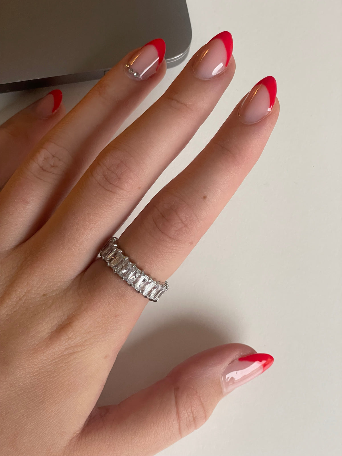 Woman wearing silver eternity ring with emerald-cut crystals on finger in titanium steel
